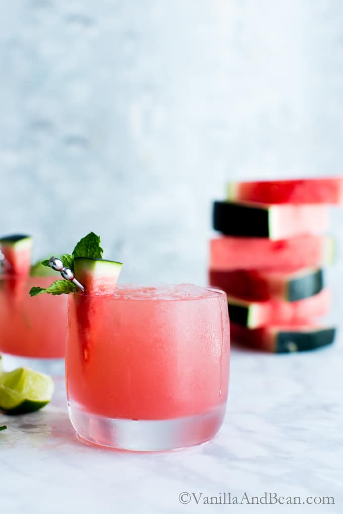 Watermelon Mojitos in ice filled glasses garnished with a watermelon wedge. 