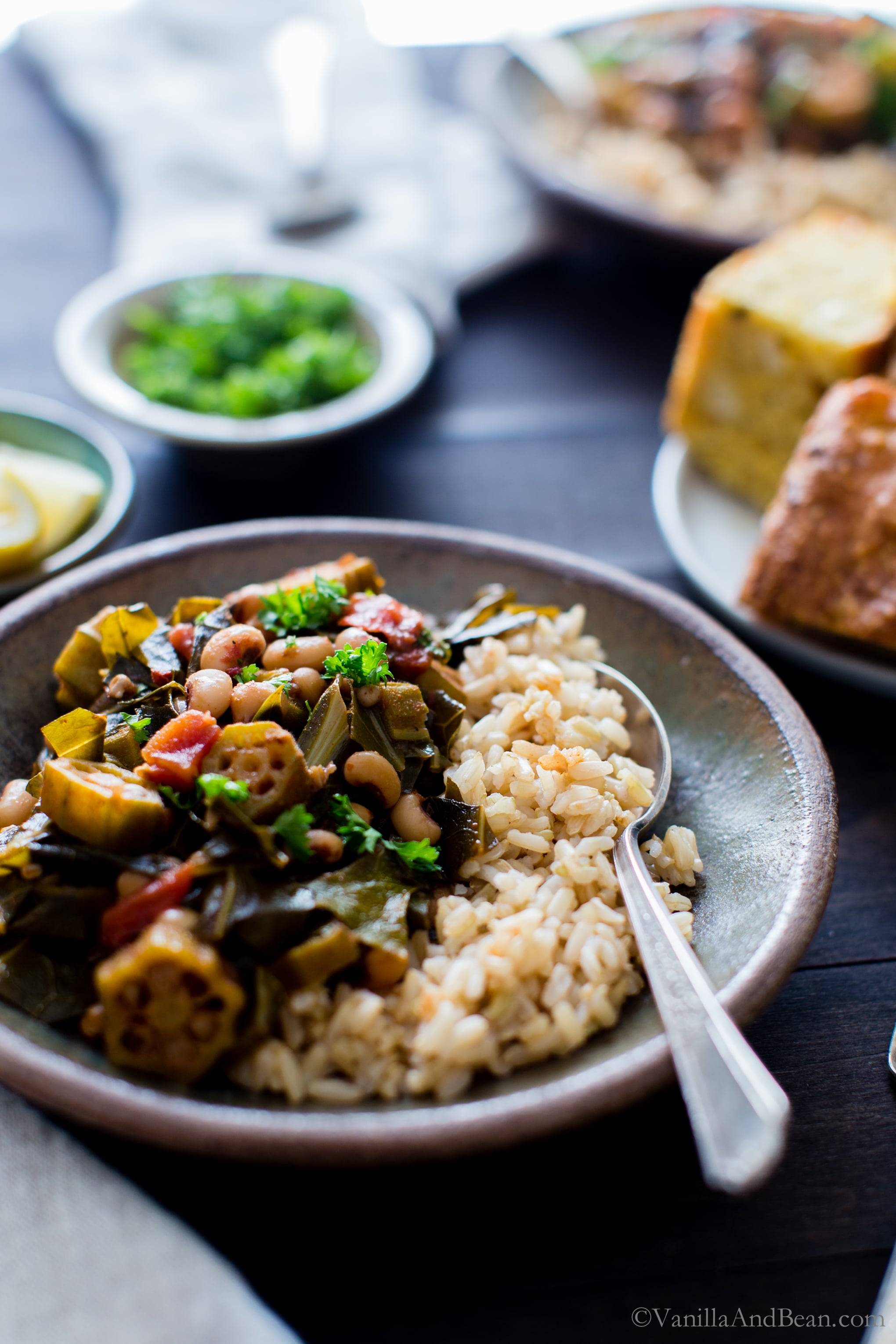 Harissa Stewed Black-Eyed Peas with Okra and Collard Greens in a bowl with brown rice ready for sharing. 
