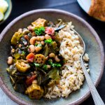 Harissa Stewed Black-Eyed Peas with Okra and Collard Greens in a bowl with brown rice ready for sharing.