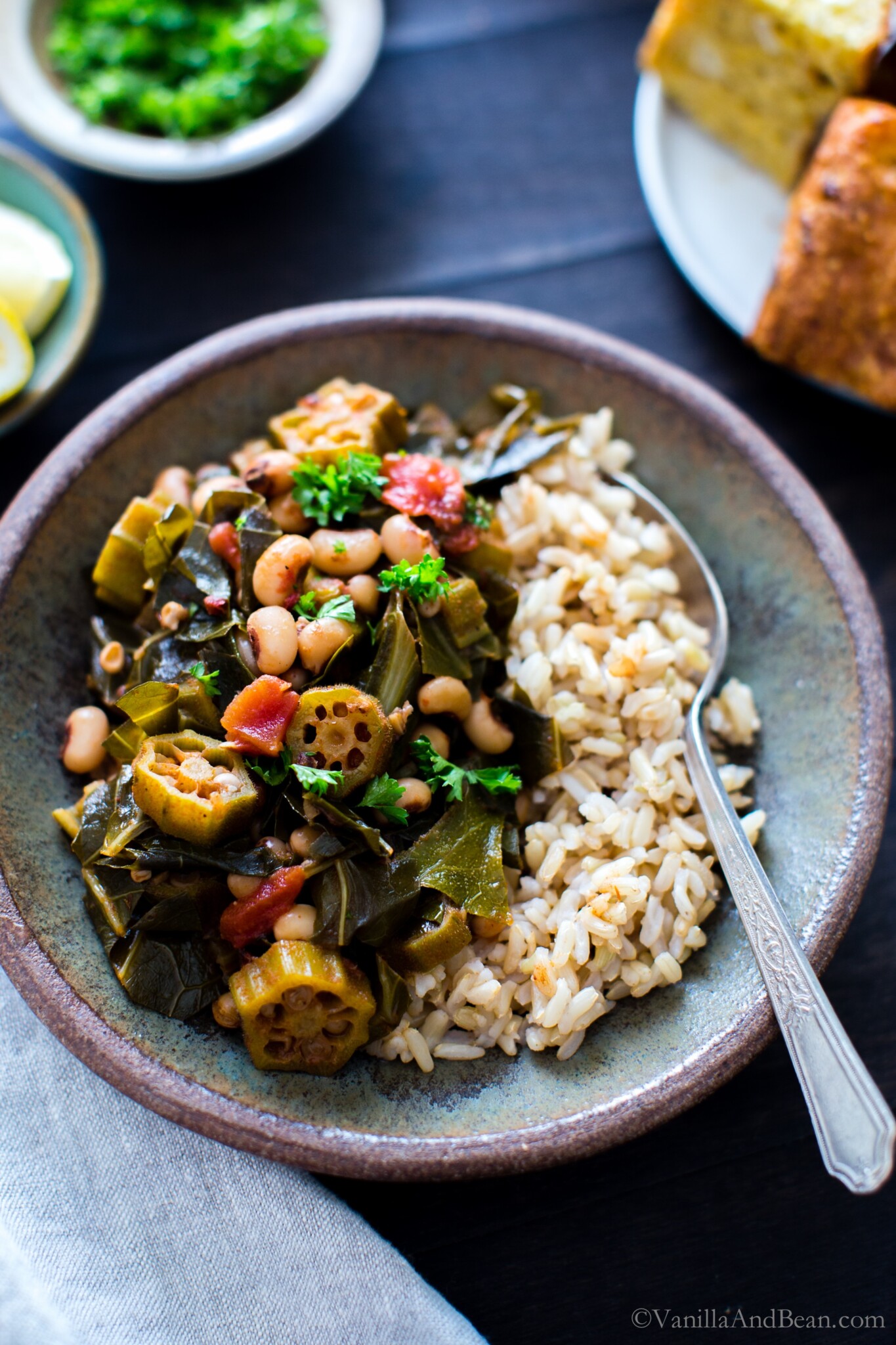 Harissa Stewed Black-Eyed Peas with Okra and Collard Greens in a bowl with brown rice ready for sharing.
