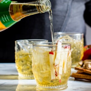 Topping sangria and ice filled glasses with sparkling apple.