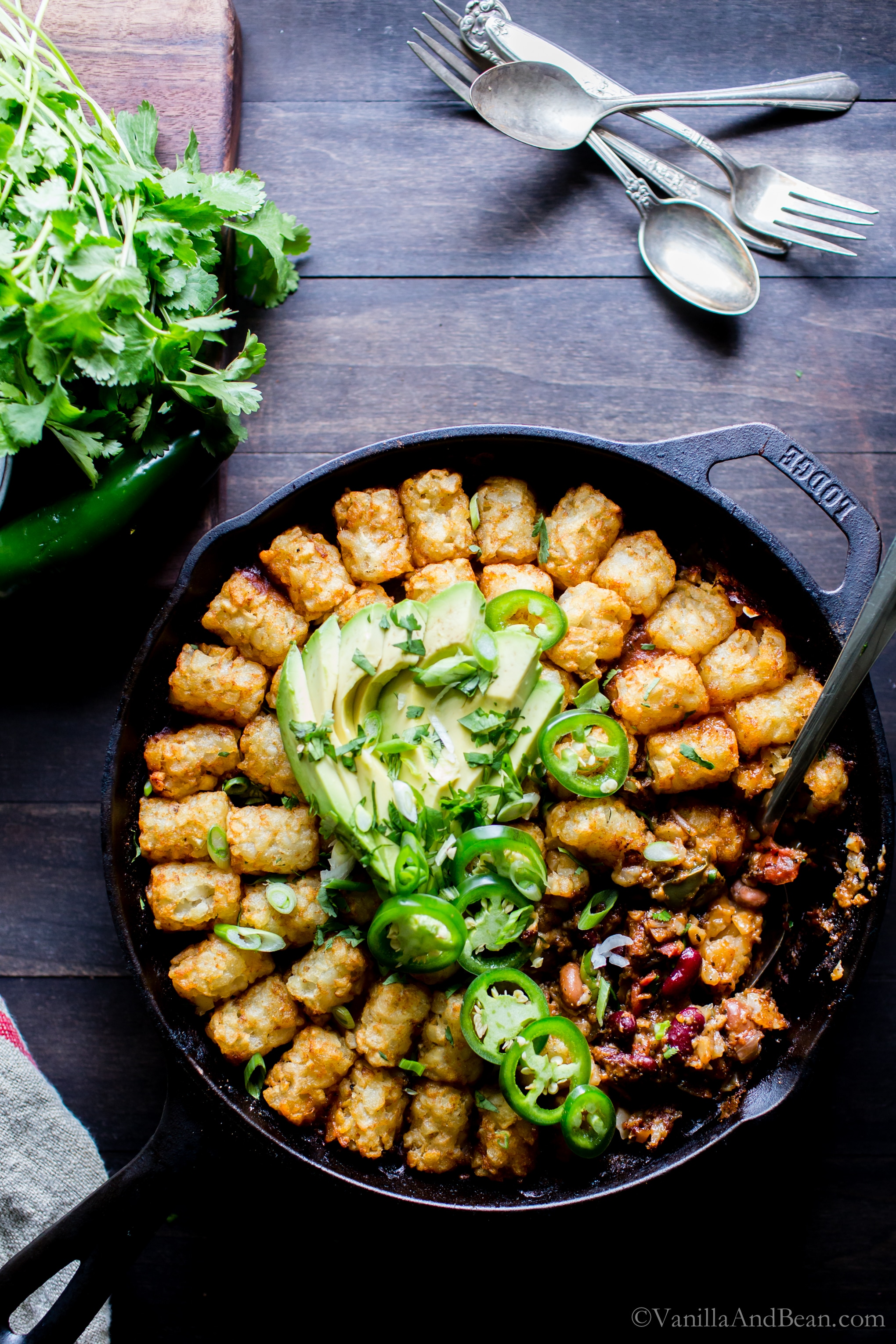 Vegetarian Chili Tater Tot Hotdish in a skillet with avocado and jalapeños on top, ready for sharing! 