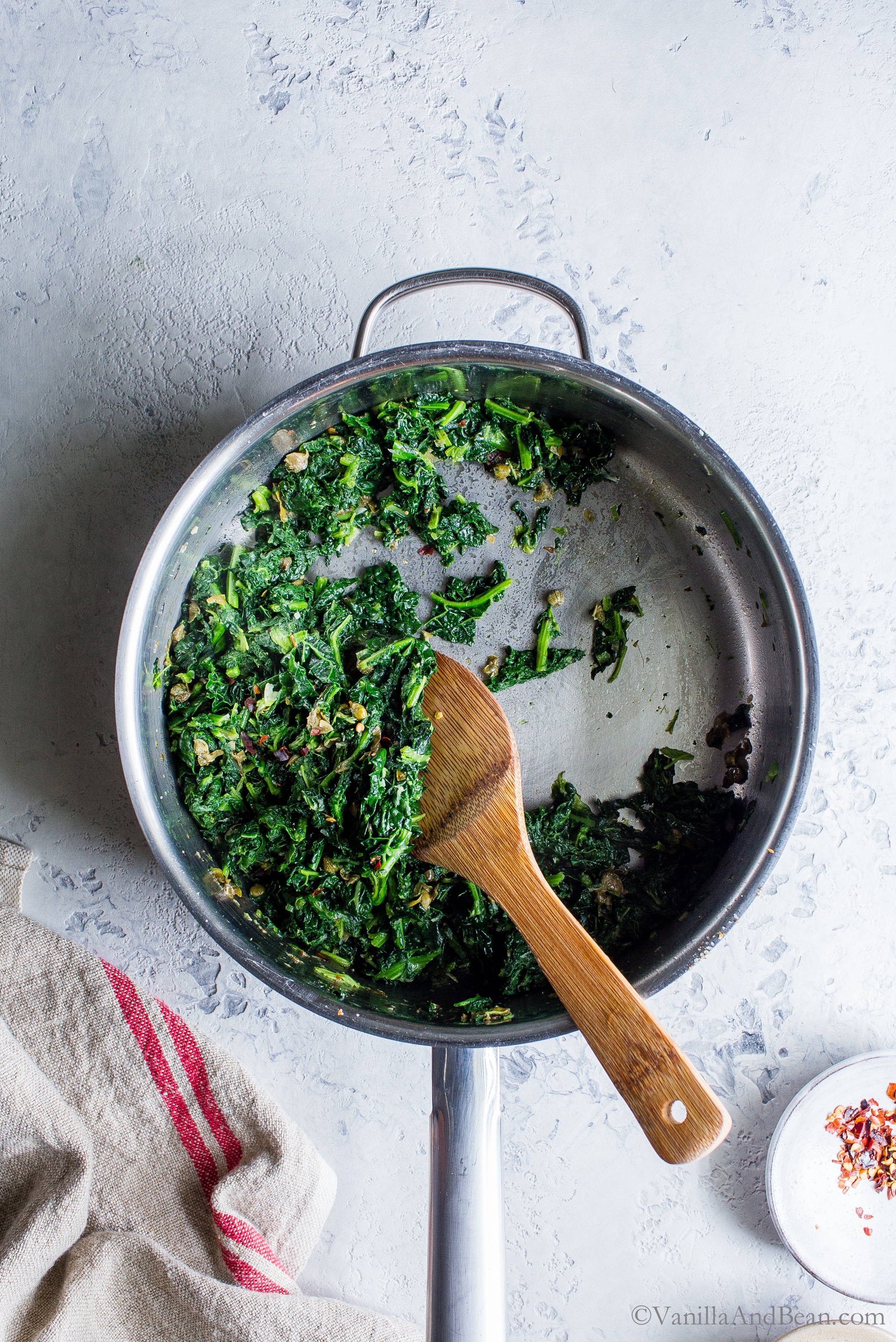 Stirring the blanched kale into the sauce. 