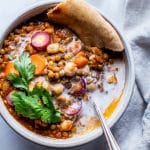 Moroccan chickpea stew in a bowl garnished with pita and cilantro.