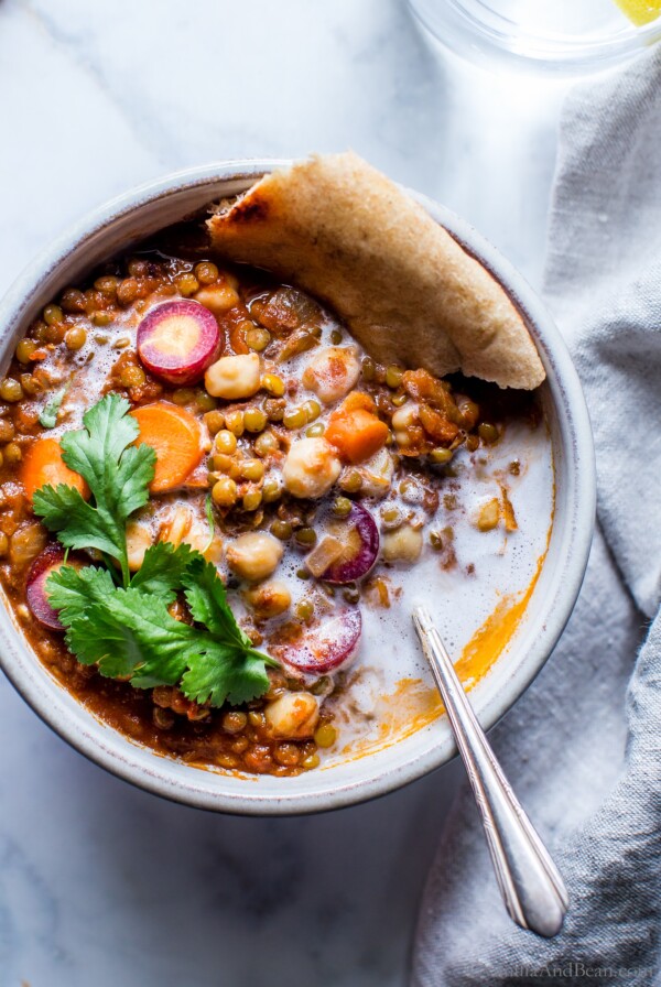 Moroccan chickpea stew in a bowl garnished with pita and cilantro.