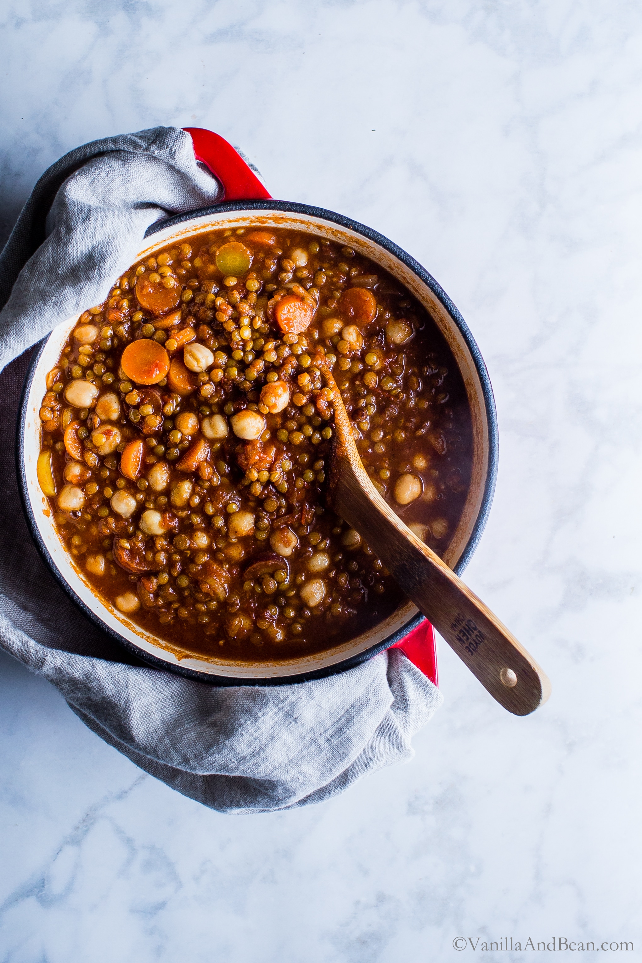 Moroccan Lentil Chickpea Stew in a Dutch oven with a stir spoon. 