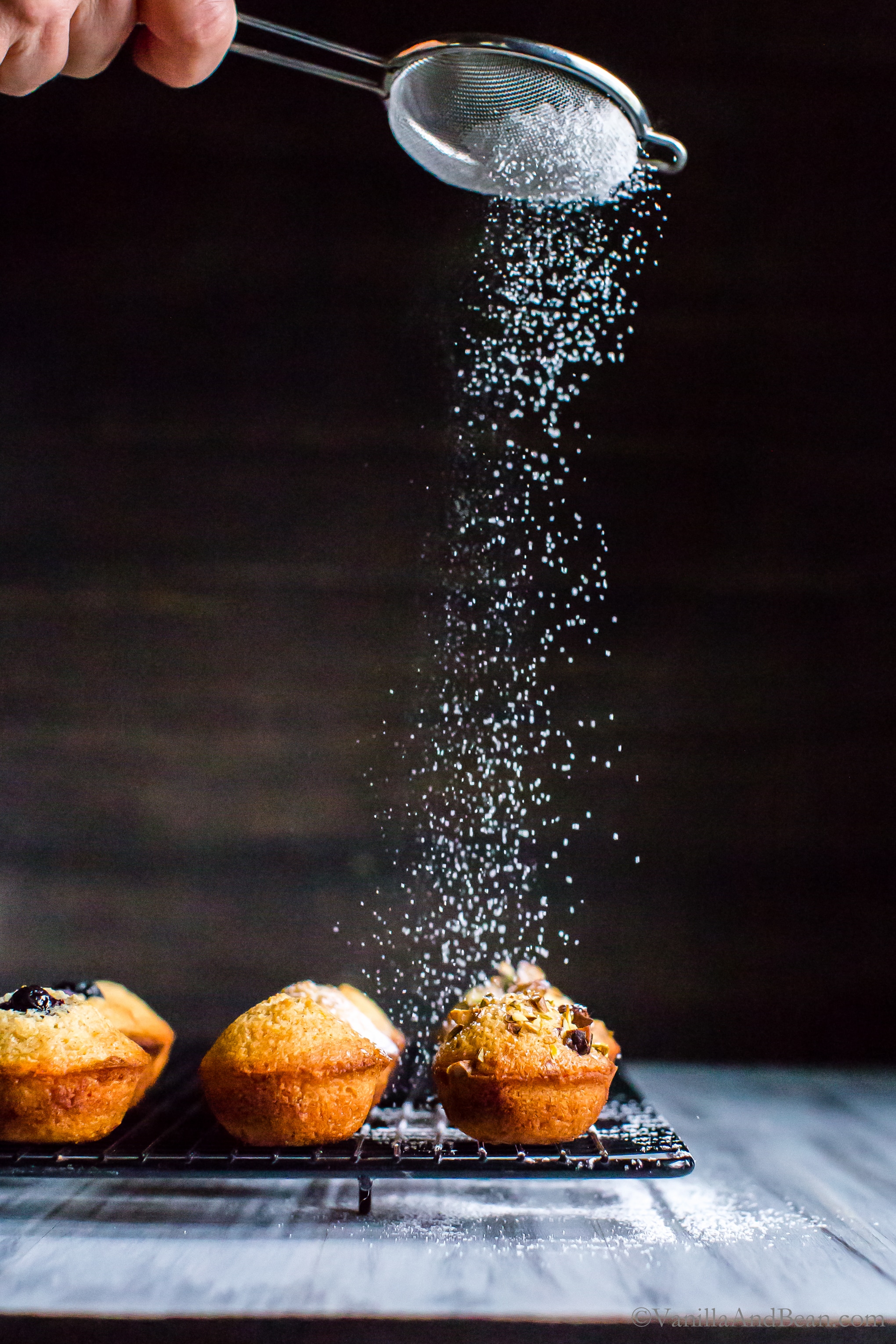 Dusting powder sugar over the Almond-Orange Mini Tea Cakes with Brown Butter.