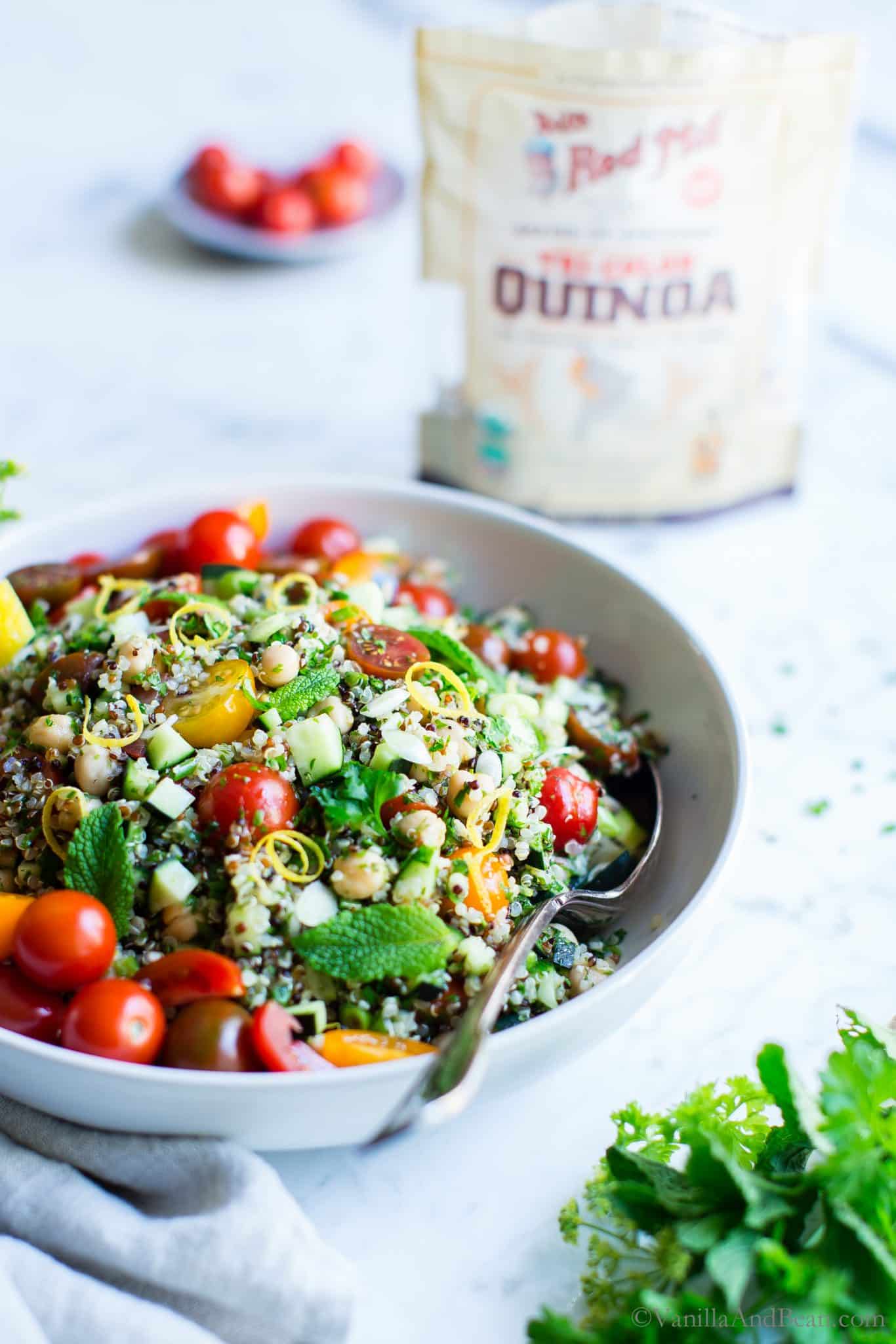 Quinoa Tabbouleh Salad with Chickpeas in a big bowl and a bag of quinoa in the background. 