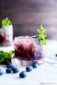 Fresh Blueberry Mojitos in a cocktail glass with a sprig of mint.