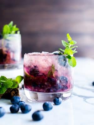 Fresh Blueberry Mojitos in a cocktail glass with a sprig of mint.