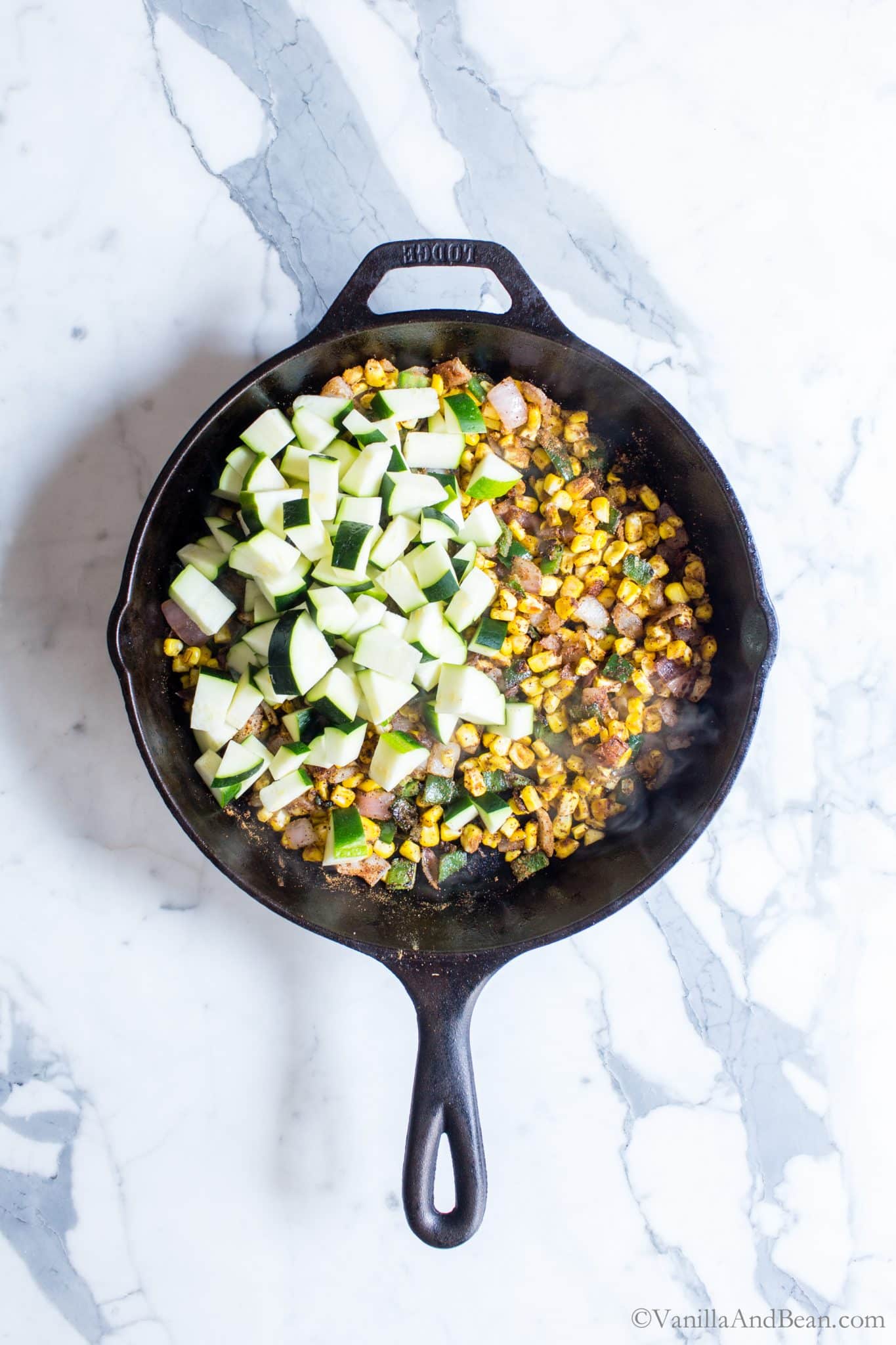 Adding zucchini to the corn and spices. 