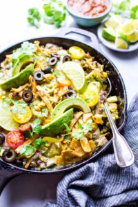 Easy vegetarian green enchiladas in a skillet with a spoon ready for sharing.