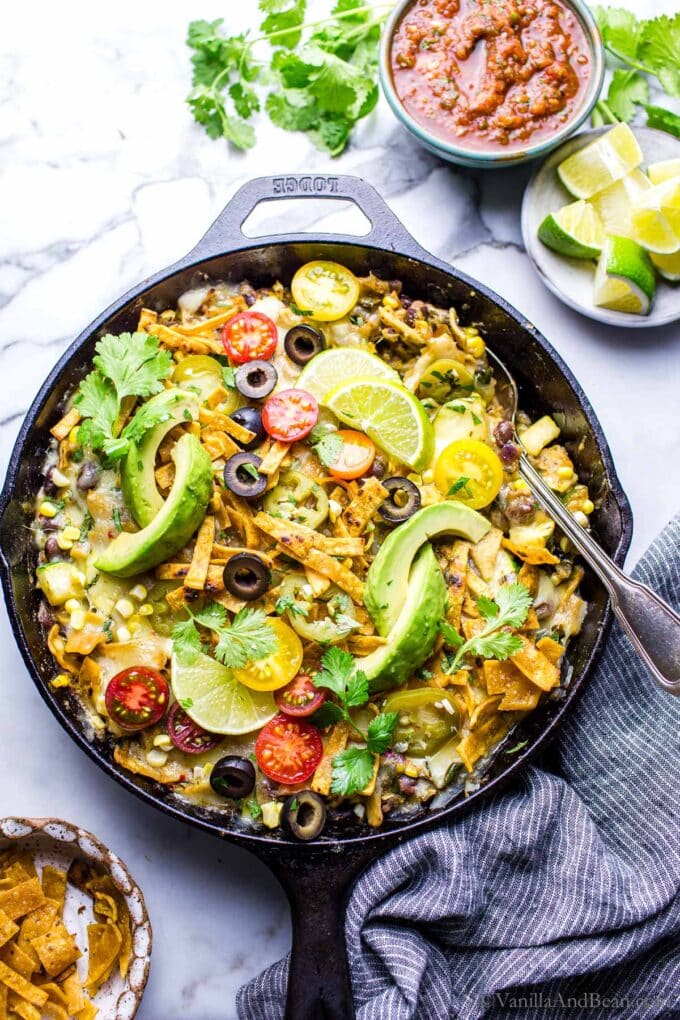 Vegetarian salsa verde enchiladas in a skillet with a spoon, ready for serving.