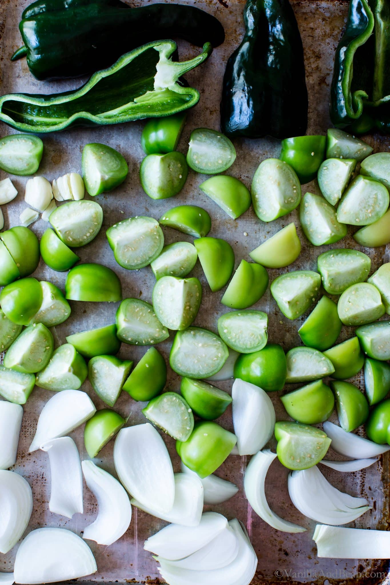 Raw ingredients on a sheet pan for Roasted Tomatillo Salsa.