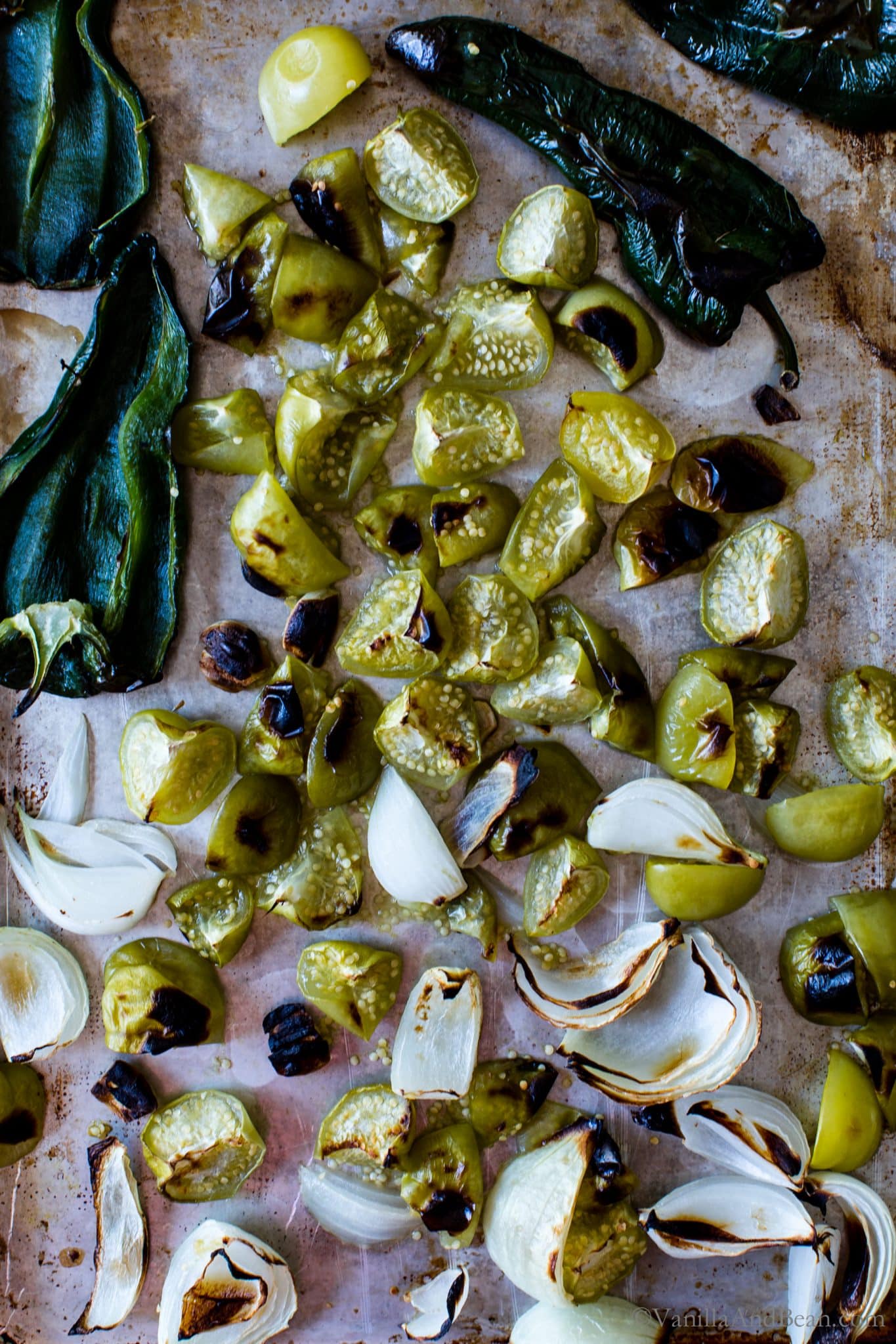 Roasted ingredients on a sheet pan for Roasted Tomatillo Salsa.