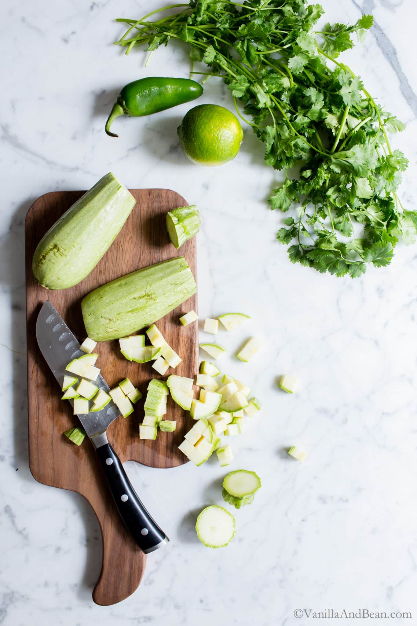 Dicing fresh zucchini on a cutting board. 