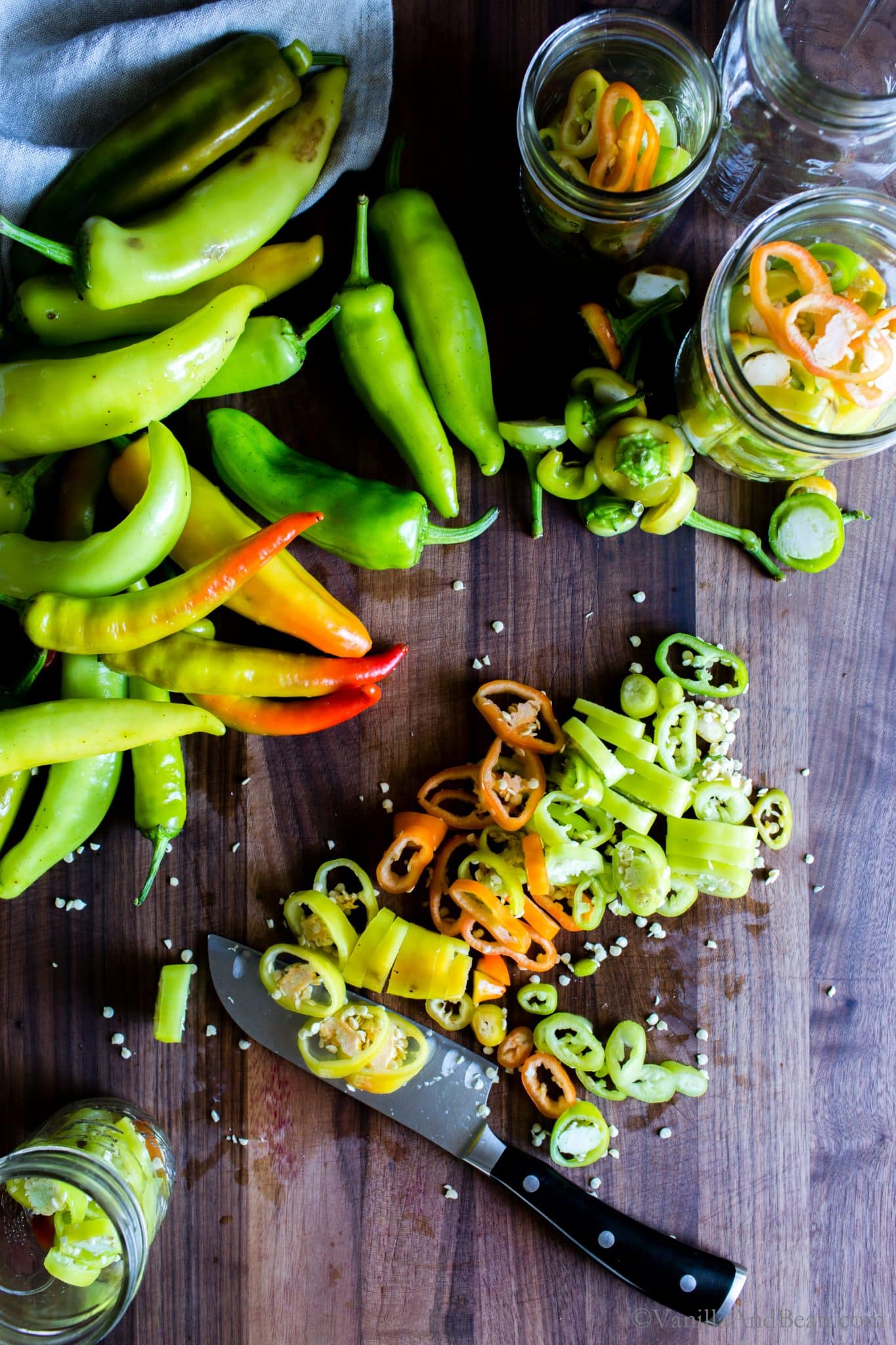 Chopping Hungarian wax peppers and packing pickling jars with the sliced peppers. . 