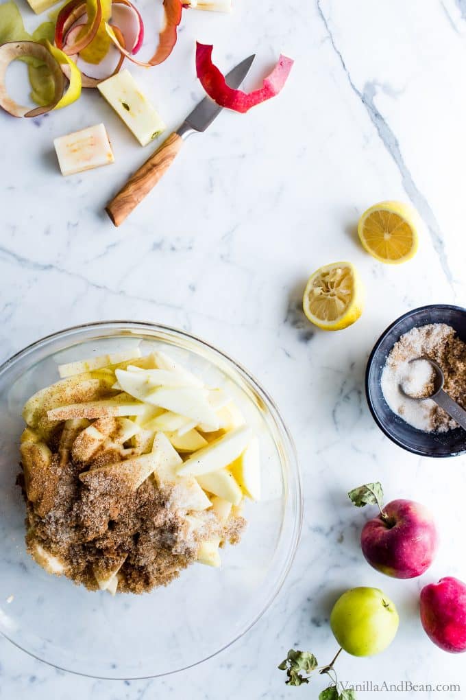Mixing raw apples in a bowl with spices and sugar.