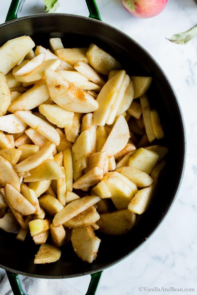 Cooking raw apples in a Dutch oven with spices and sugar.