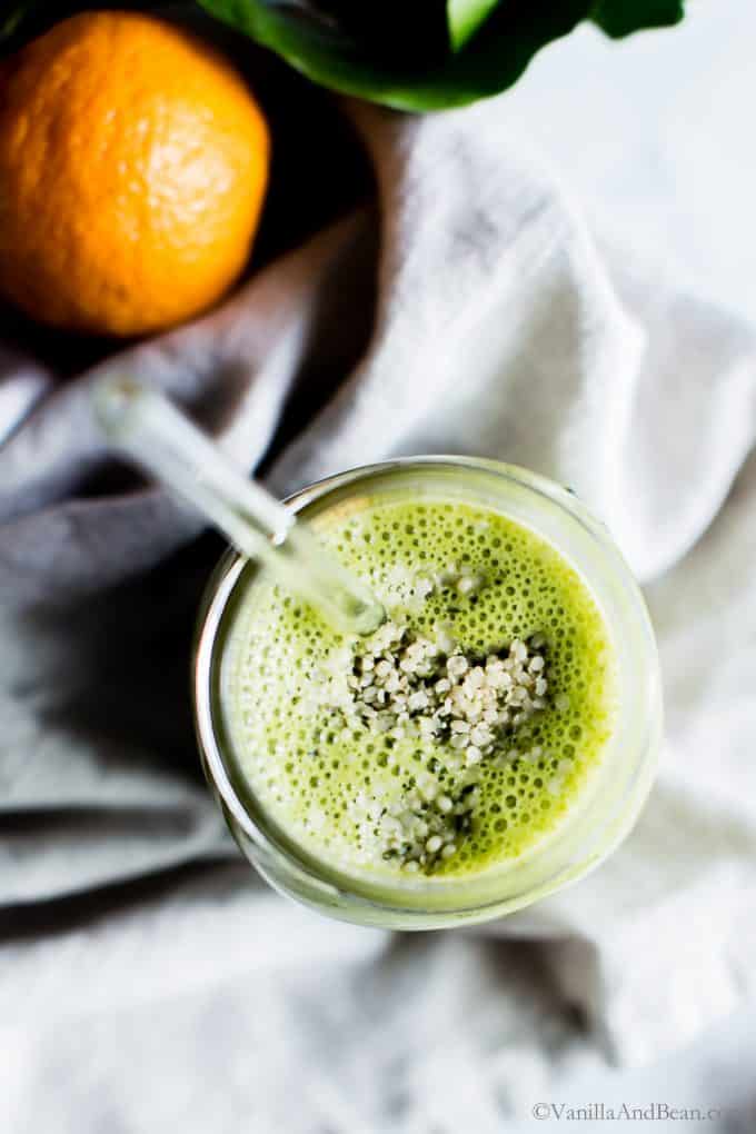 Looking into a jar full of Matcha Smoothie with hemp hearts sprinkled on top. 