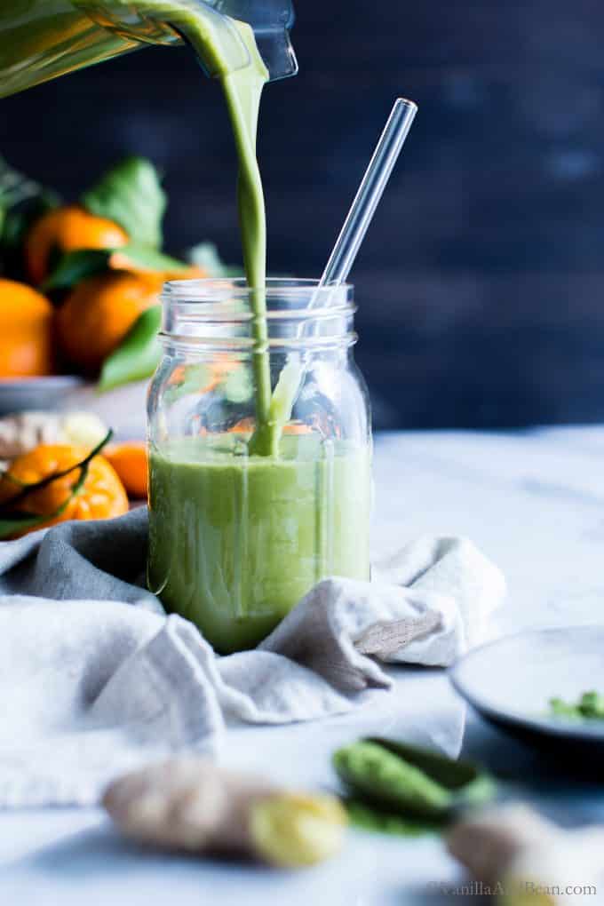 Pouring Green Tea Smoothie into a jar surrounded by oranges