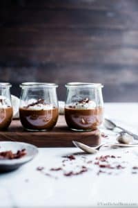 Chocolate Pots de Crème on a serving board being sprinkled with chocolate.