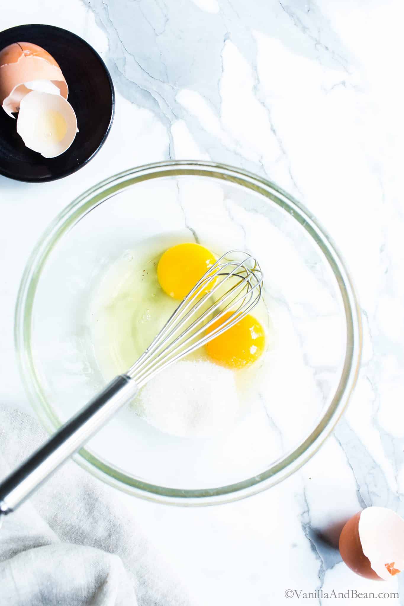 Two cracked eggs and whisk in a bowl. 