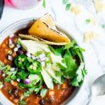 Slow Cooker Vegetarian Taco Soup in a bowl garnished with cilantro, peppers, avocado and tortilla.