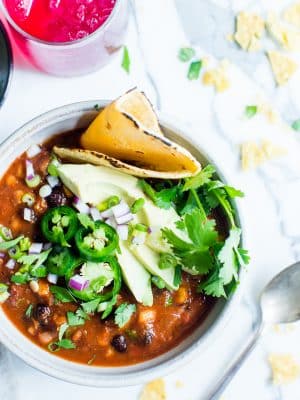 Slow Cooker Vegetarian Taco Soup in a bowl garnished with cilantro, peppers, avocado and tortilla.