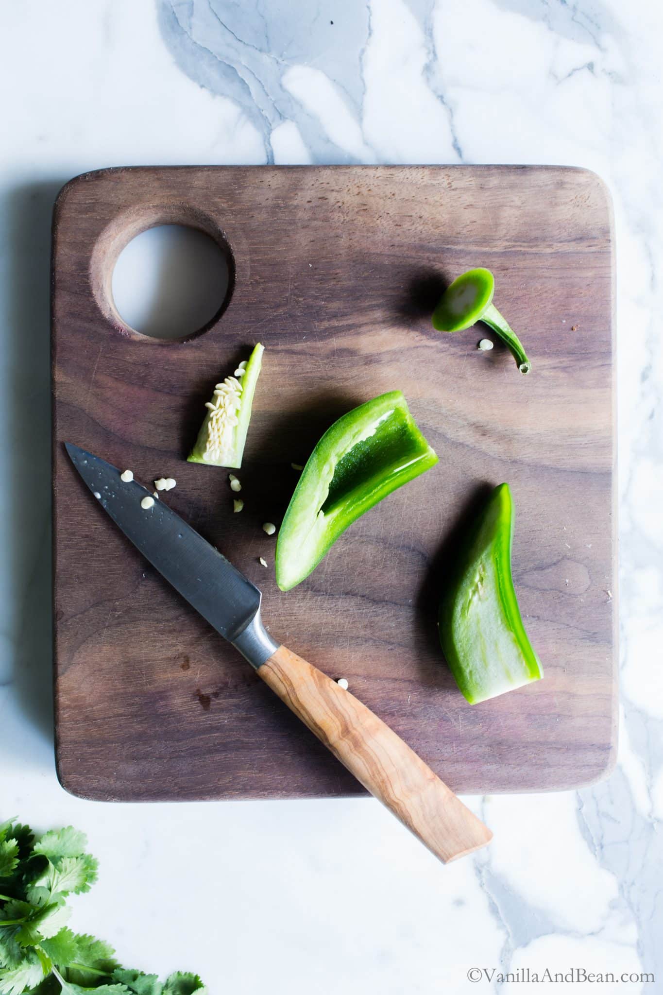 Removing seeds in a jalapeno pepper on a cutting board. 
