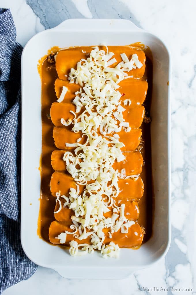 Vegetarian Enchiladas in a baker covered in cheese ready to be baked. 