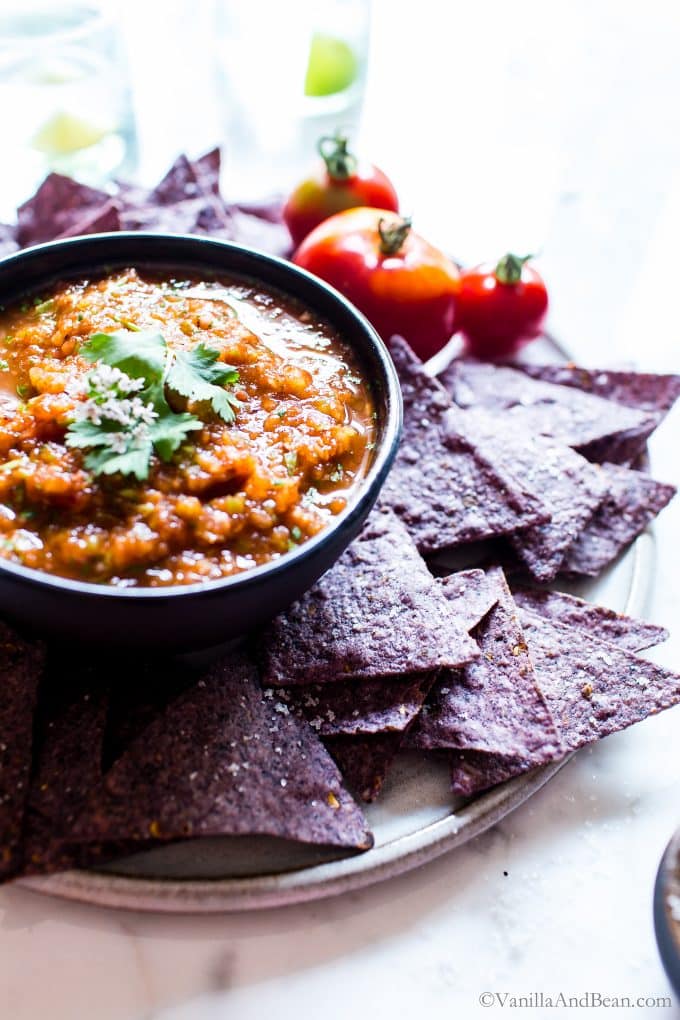 Easy Mexican Chipotle Salsa served with purple chips and tomatoes.