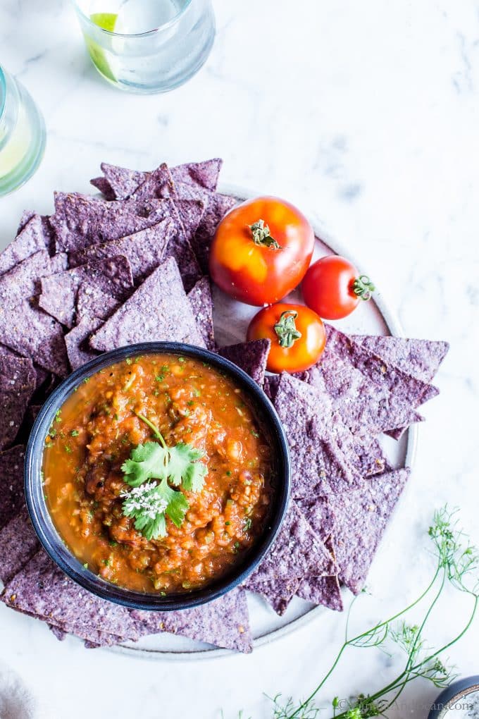 Delicious Red Mexican Chipotle Salsa in a bowl on the table with tomatoes and chips on the side
