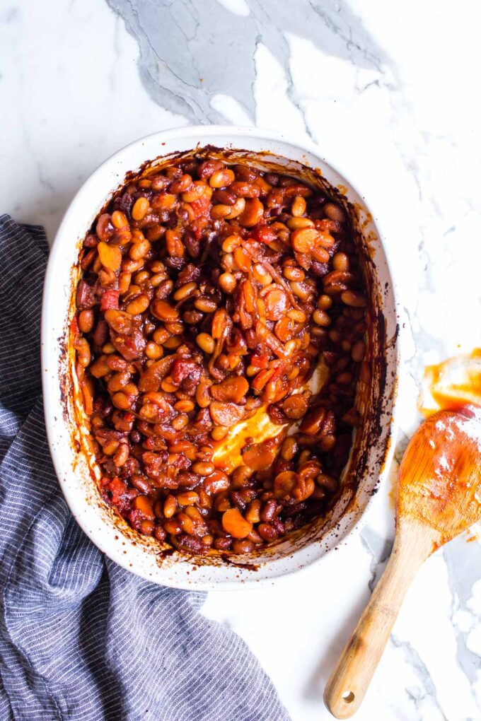 Vegetarian and Vegan BBQ Baked Beans in a baker with a saucy spoon on the side. 