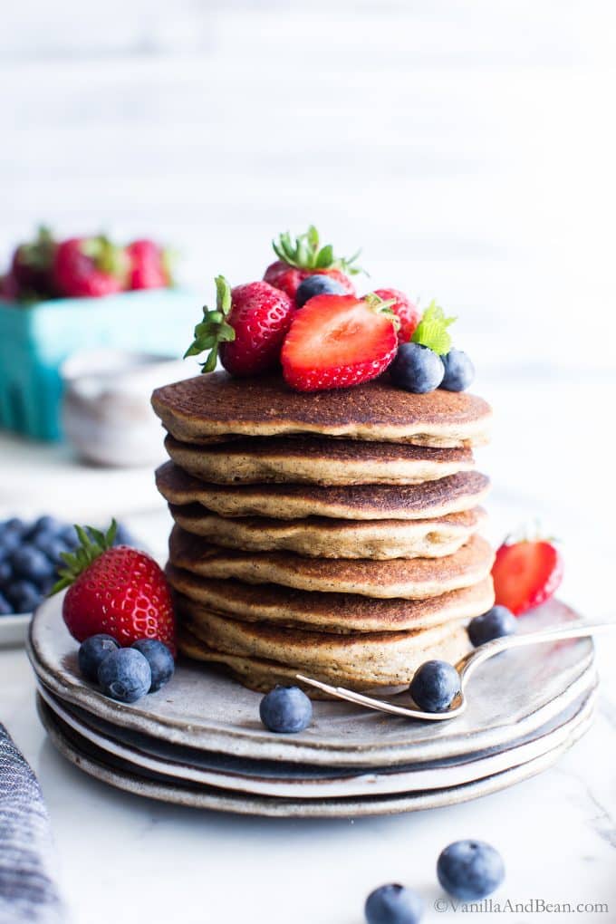 A Stack of No Flour Oatmeal Pancakes on a plate with berries on top. 