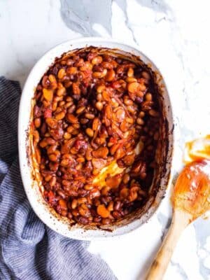 Vegetarian and Vegan BBQ Baked Beans in a baker with a saucy spoon on the side.