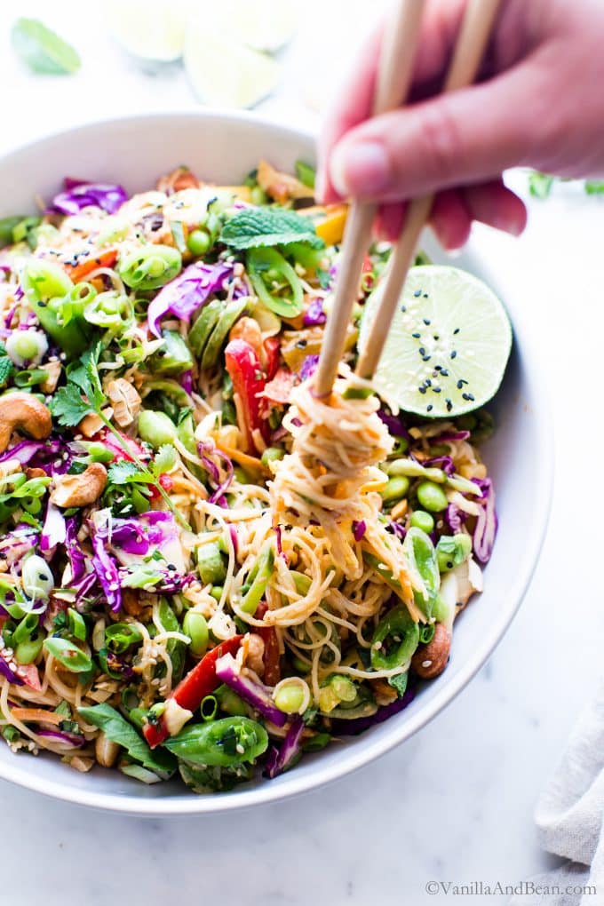 Asian Peanut Noodle Salad in a large serving bowl with noodles being twirled with chopsticks. 