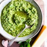 Almond basil pesto in a bowl with a spoon.