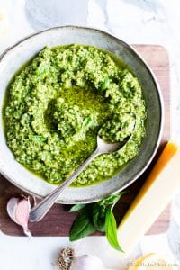 Almond basil pesto in a bowl with a spoon.
