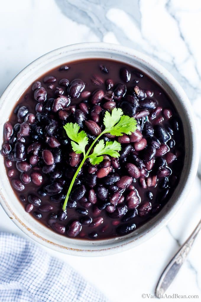 A bowl of cooked black beans in a bowl with cilantro.