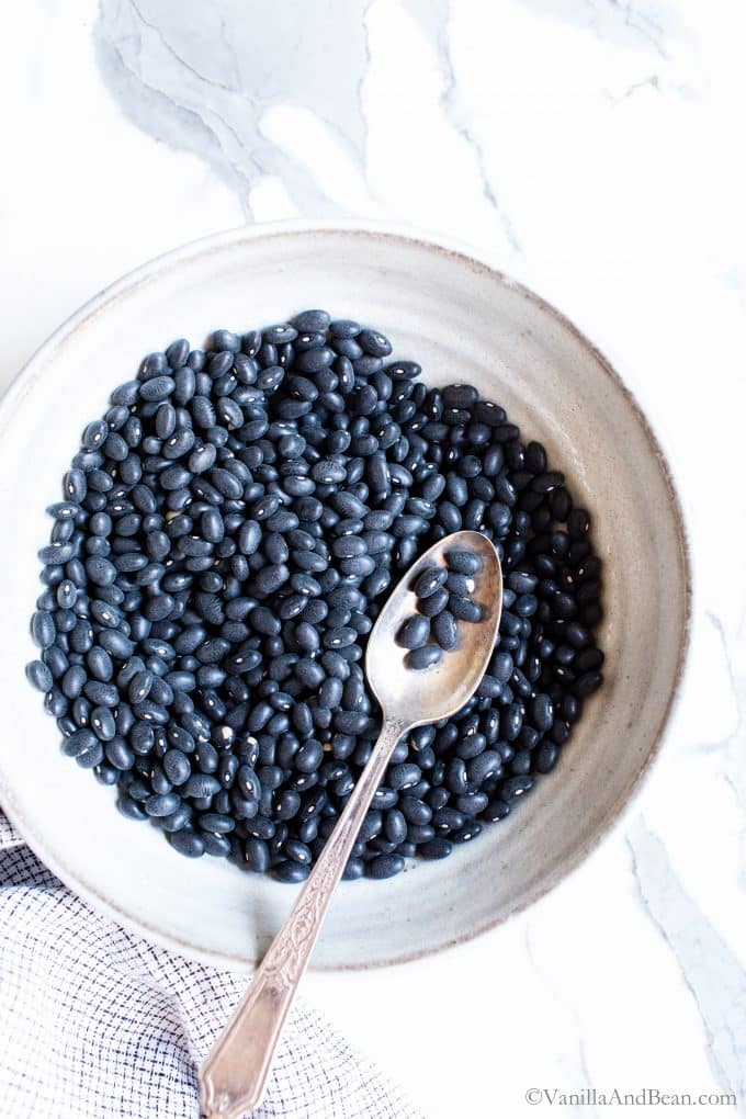 A Bowl of Dry Black Beans with a spoon in the bowl. 
