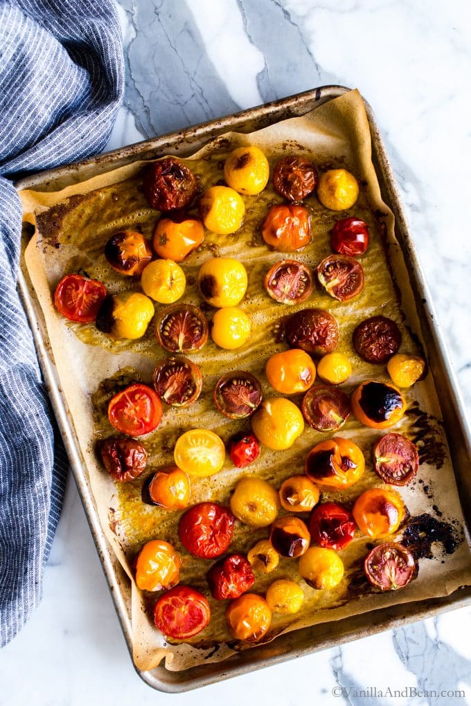 Roasted tomatoes on a parchment lined sheet pan. 