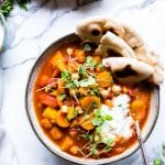 Moroccan Butternut Squash Stew topped with yogurt, microgreens and shared with Naan in a bowl.