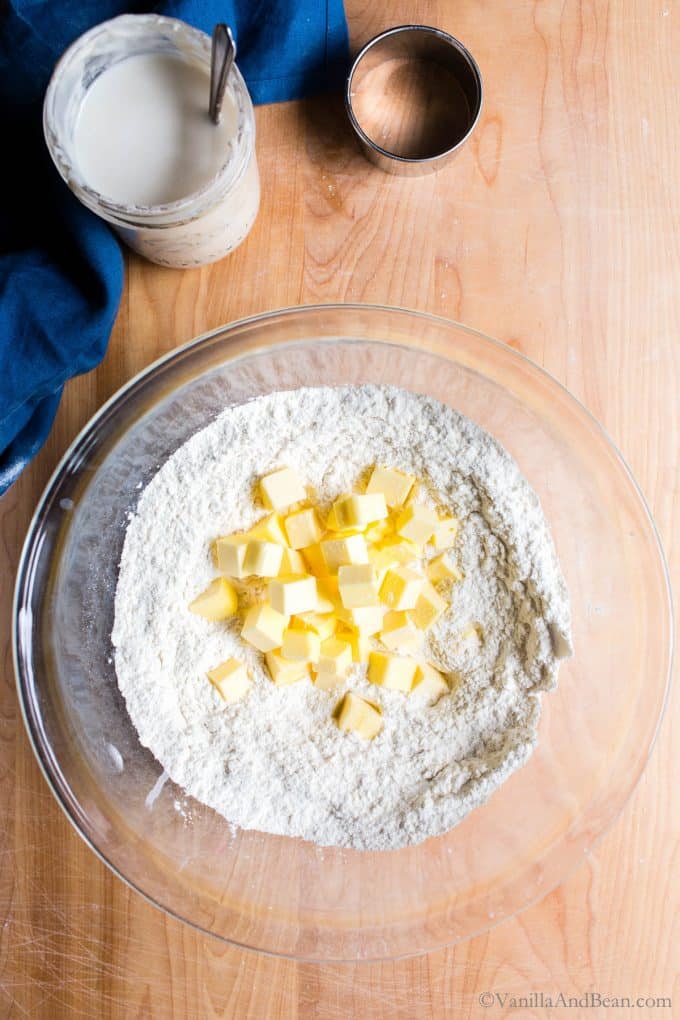 Adding cubed butter to the flour in a bowl. 