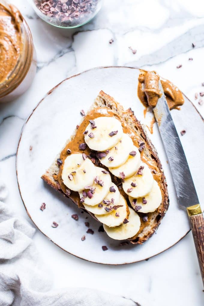 Nut Butter on Toast with Bananas on a plate sprinkled with cocoa nibs. 