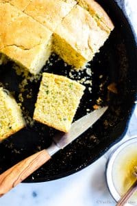 Close up of sliced Jalapeño Cheddar Cornbread in a skillet with a knife.