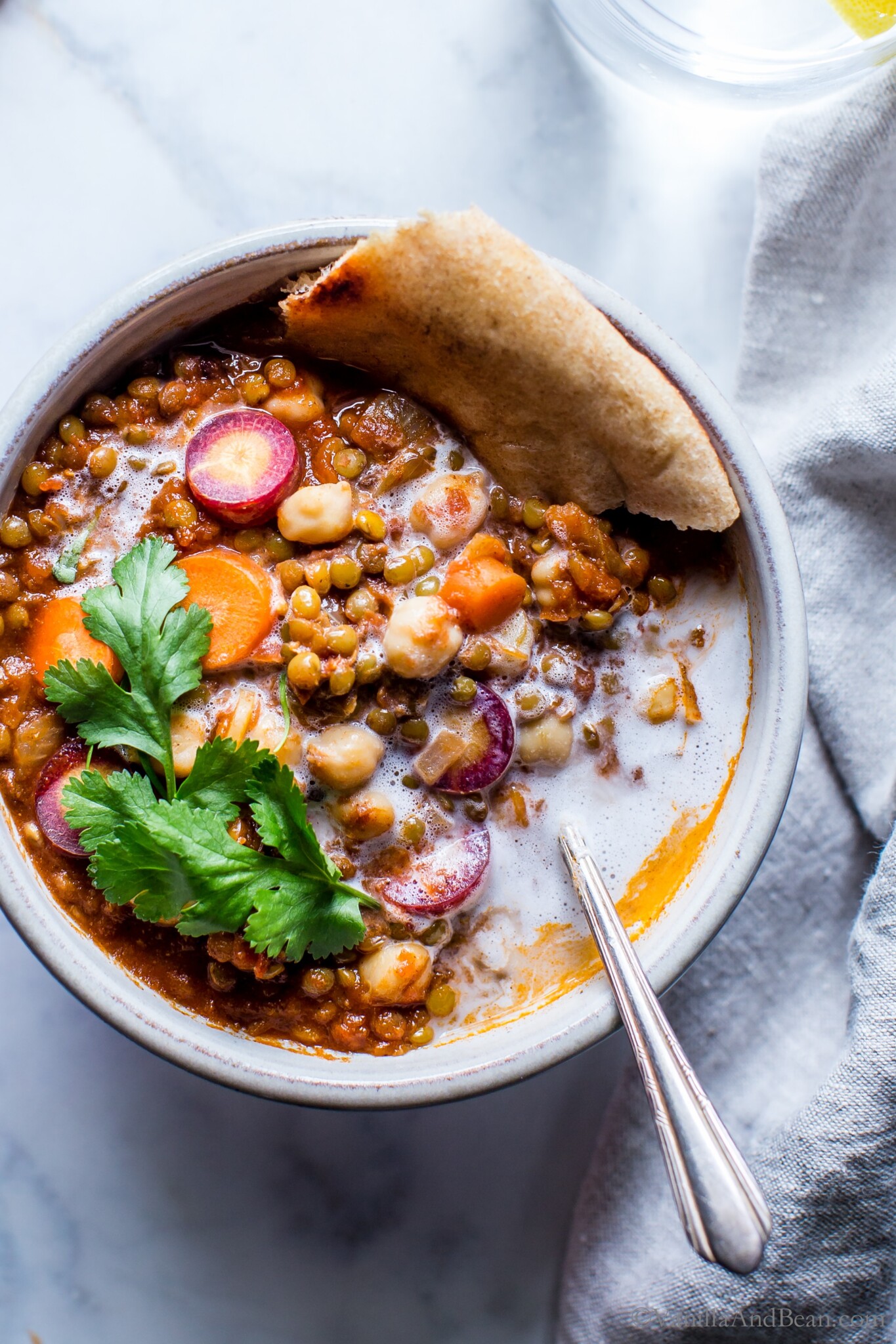 A bowl of moroccan lentil stew garnished with cilantro and pita bread.