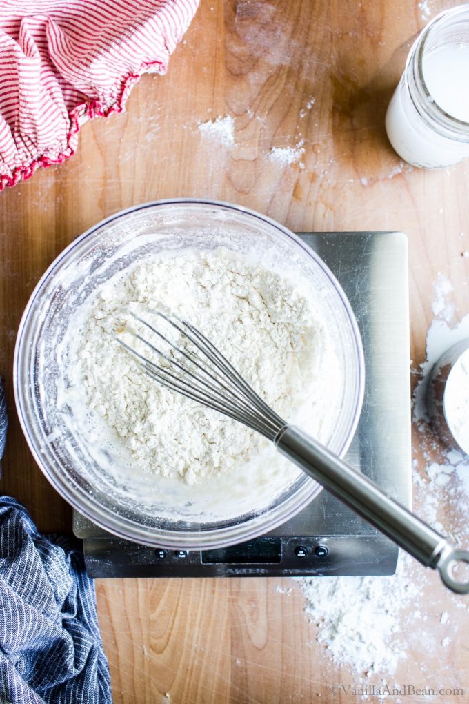 Flour and water in a bowl with a whisk in the bowl.