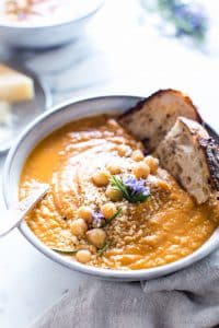 Tuscan Tomato Chickpea Soup in a bowl with two slices of sourdough dunked in.