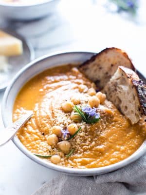Tuscan Tomato Chickpea Soup in a bowl with two slices of sourdough dunked in.